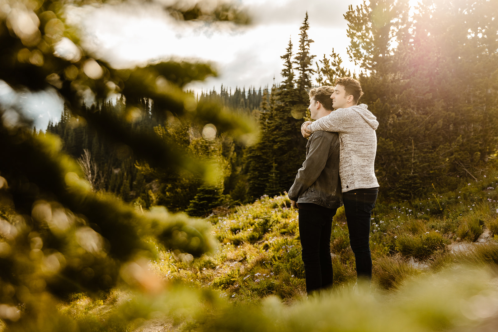 one boy hugs another from behind as they look out over the wilderness
