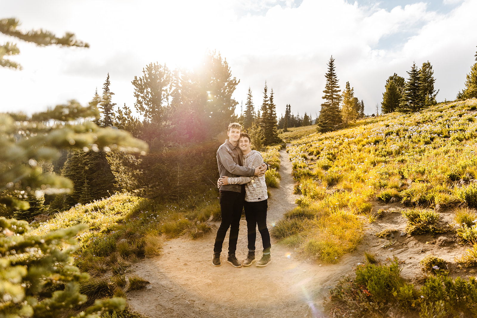 two boys hug while draped in sunlight surrounded by fields and trees