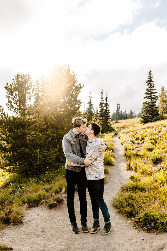 two boys look at each other  with field and trees around them during mt rainier engagement session
