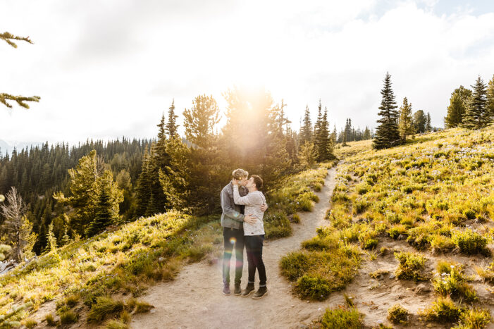 two boys hug while draped in sunlight surrounded by fields and trees