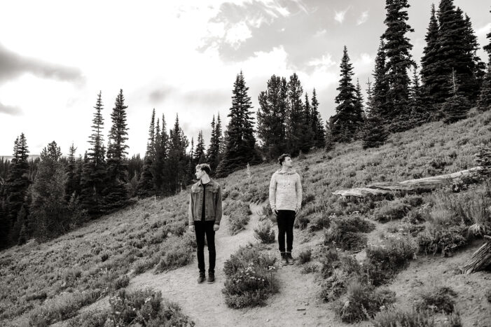 two boys hug while draped in sunlight surrounded by fields and trees