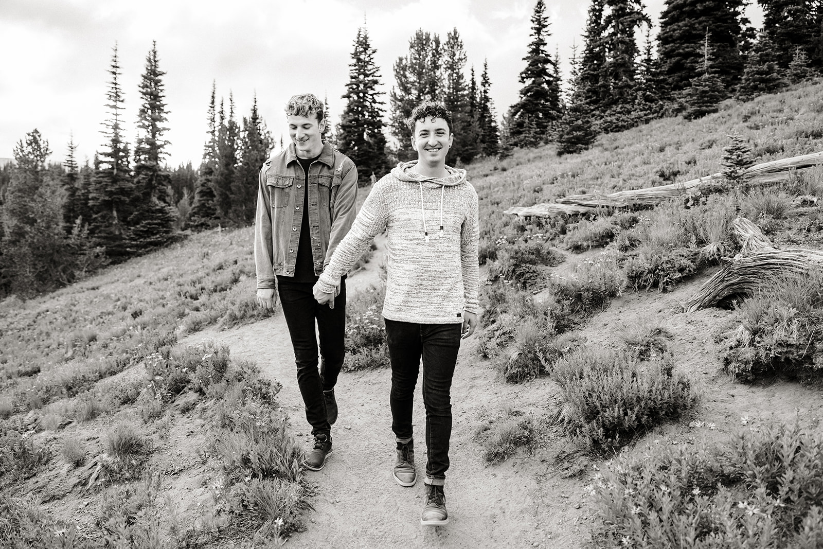 two boys walk down a path through a field with trees in the background
