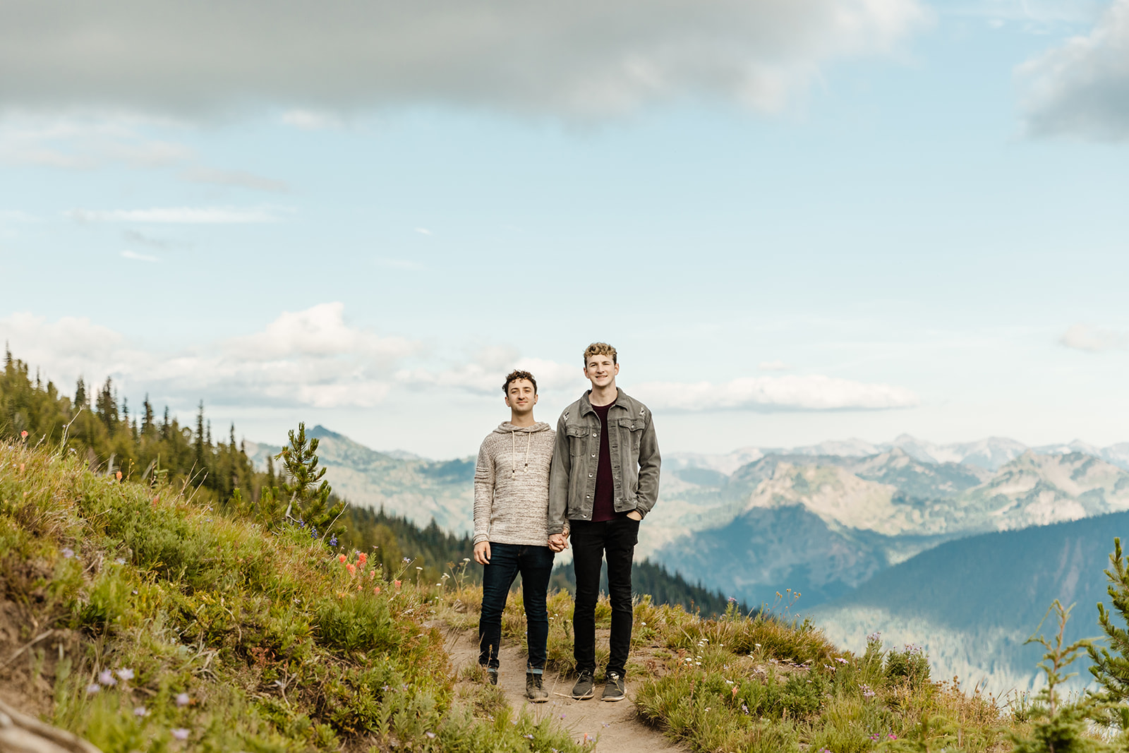 two boys walk down a path through a field with trees in the background