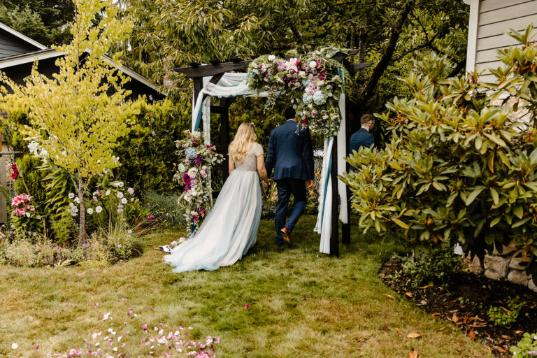 bride and groom exit backyard wedding through arch way