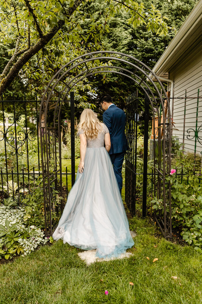 bride and groom go through arch in backyard wedding