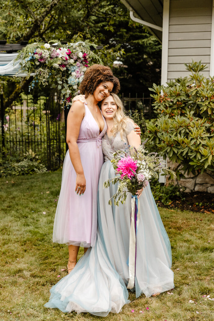 bride poses with another woman during backyard wedding