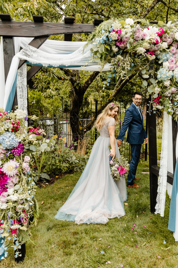 bride looks back at her dress as she walks through arch