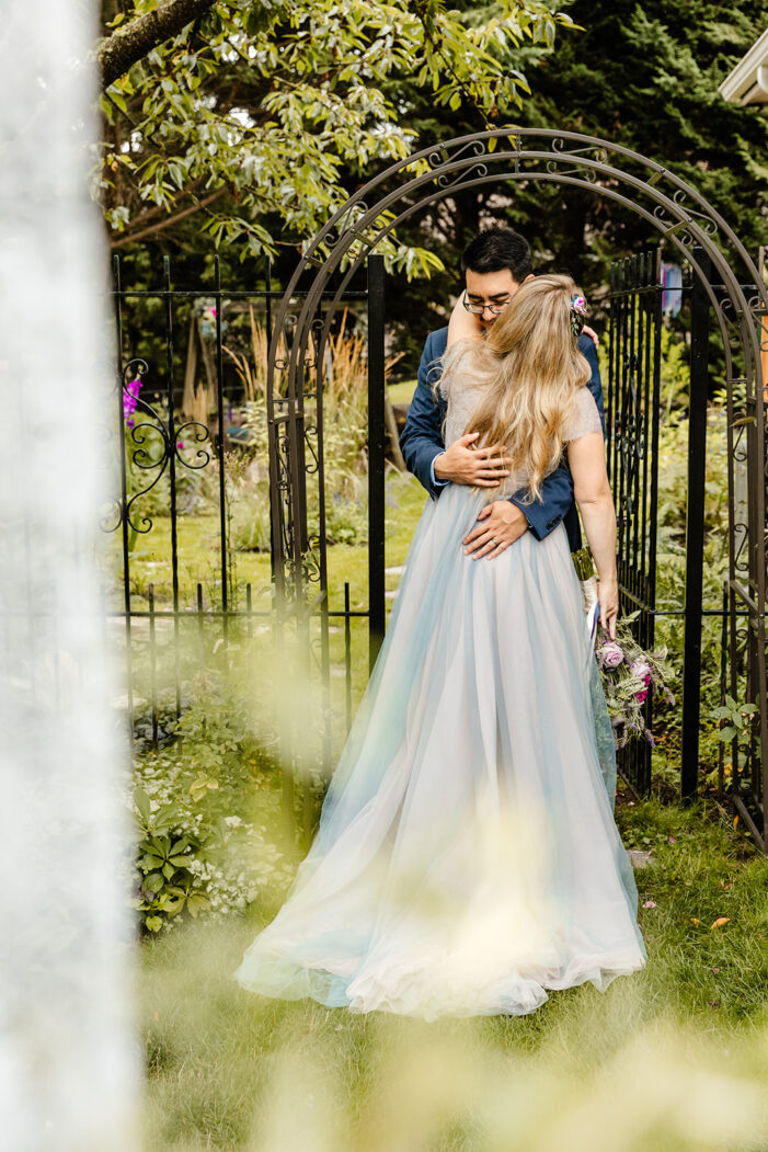 bride and groom hug amongst garden during backyard wedding