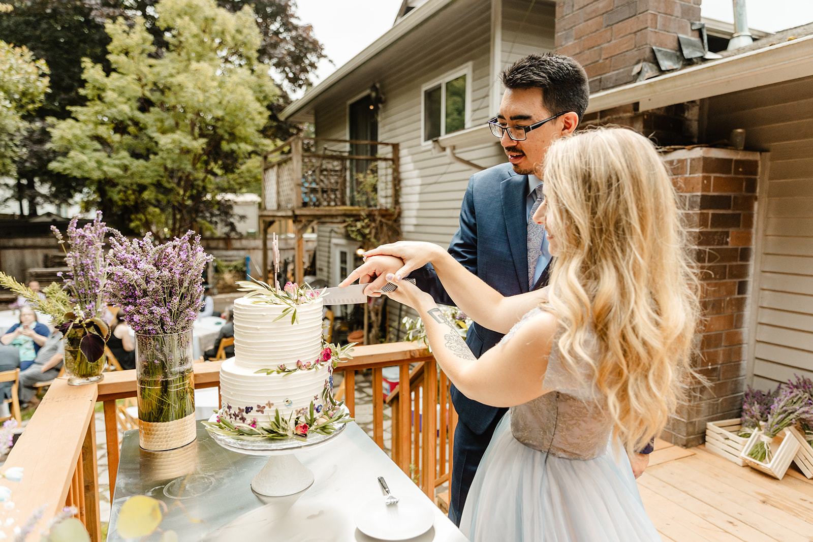 bride and groom cut a whimsical cake during backyard wedding