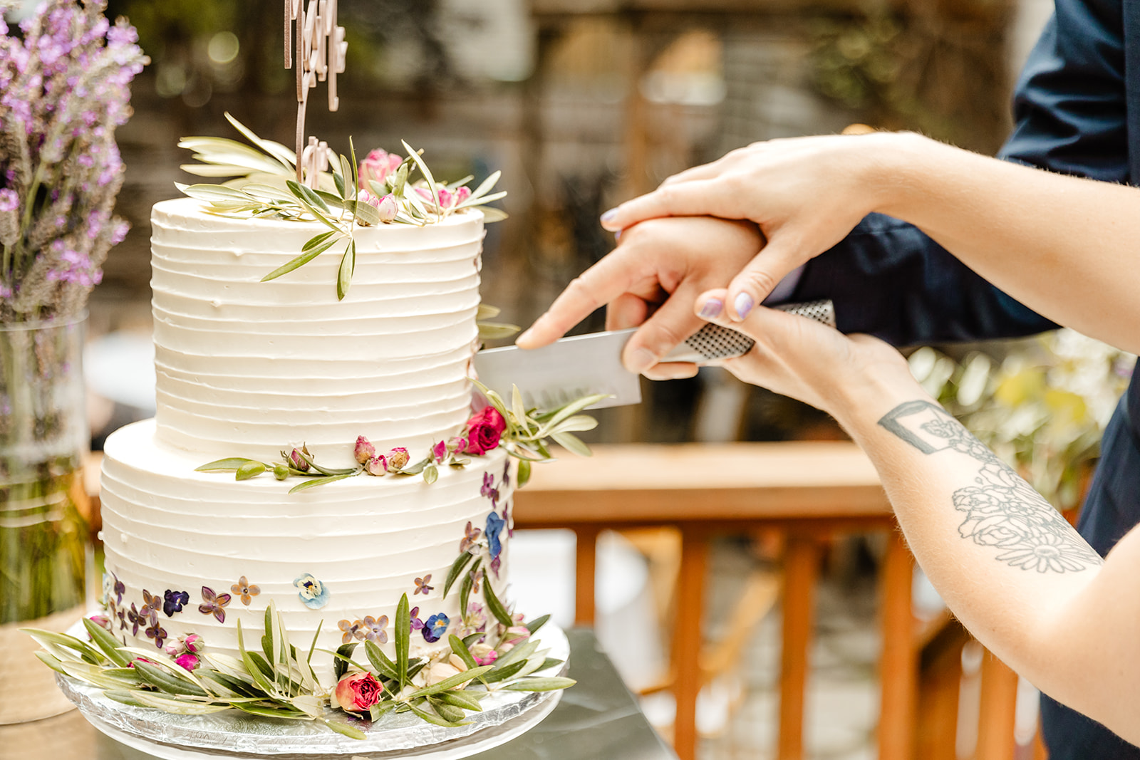 close on two hands holding a knife cutting a wedding cake