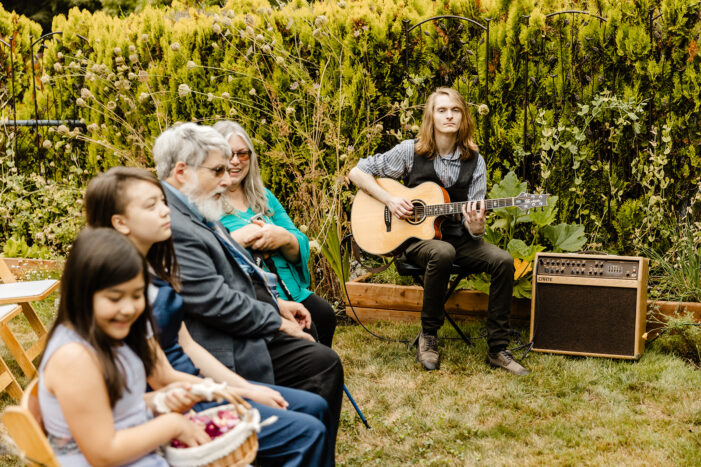 man plays guitar during backyard wedding