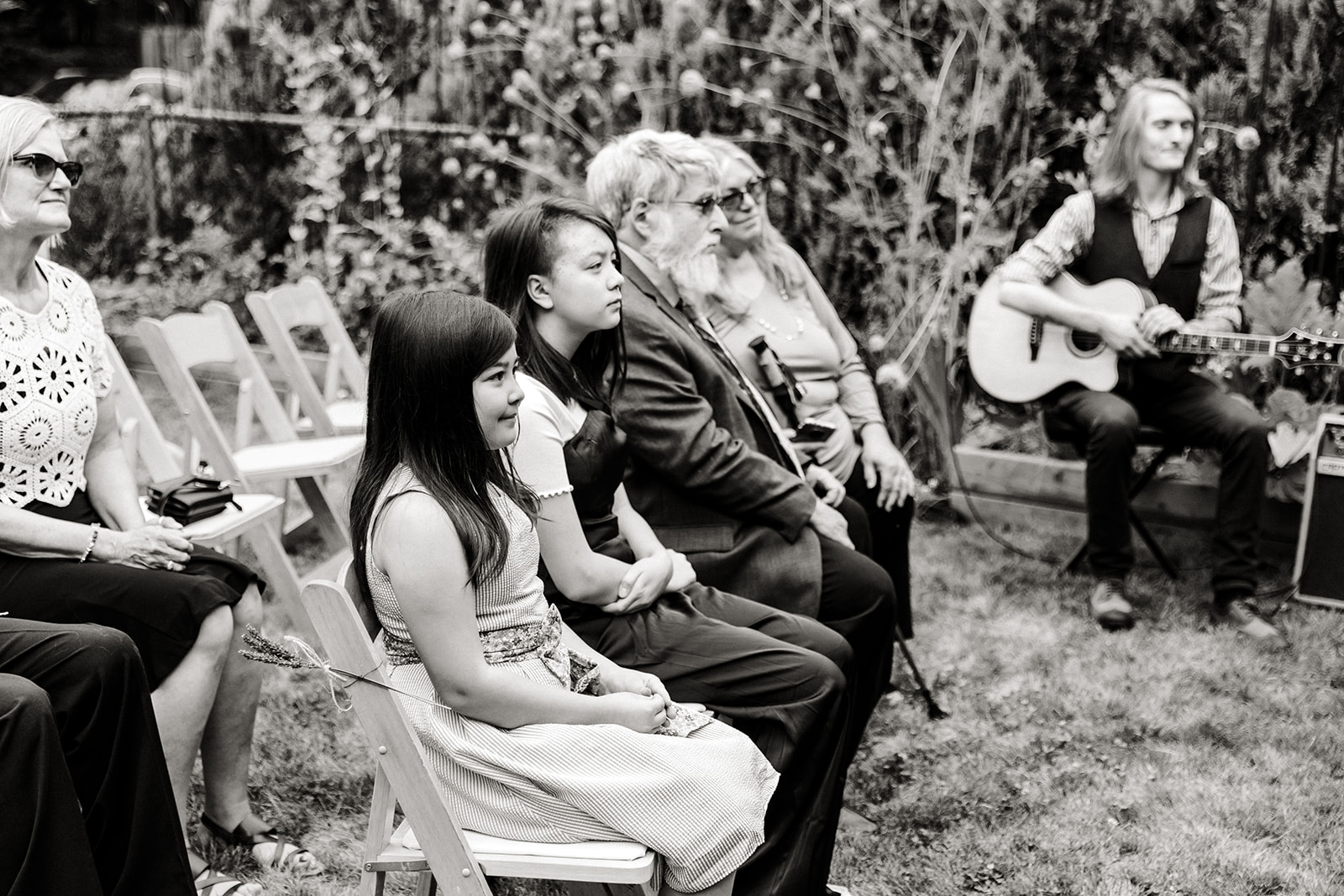 wedding guests look on during ceremony in backyard wedding