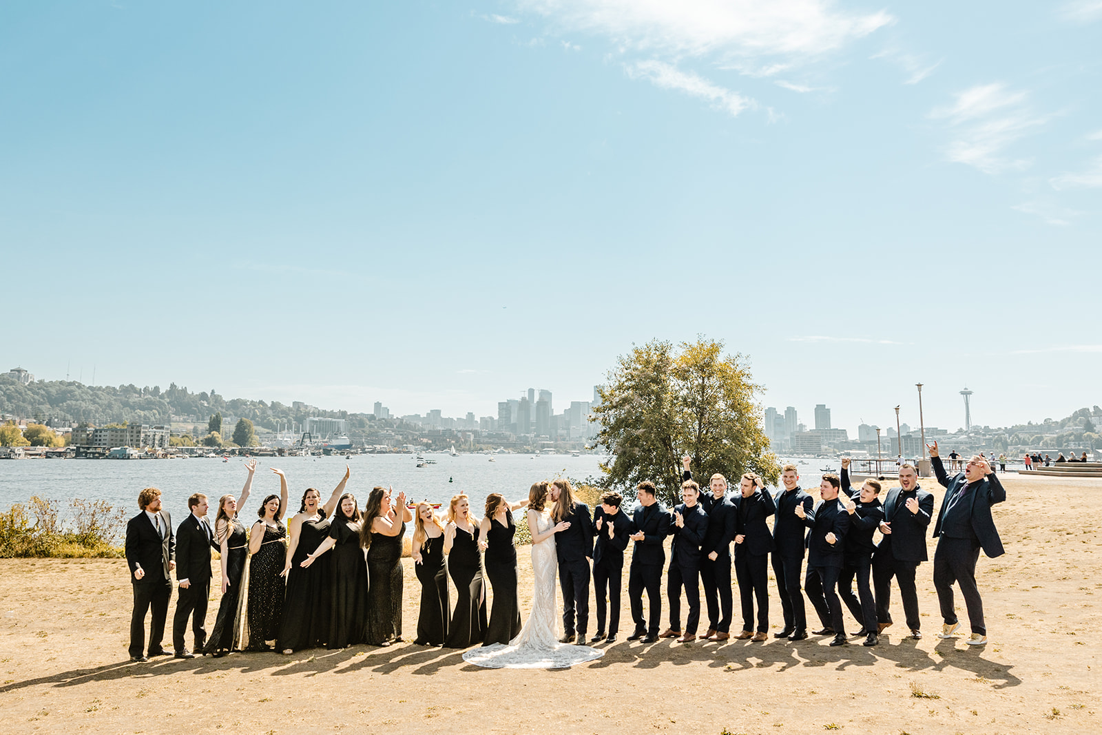 bridal party in black pose in a line together in front of seattle skyline