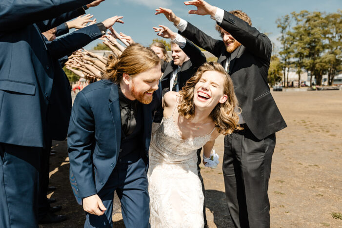 bride and groom run through tunnel of bridal party while laughing