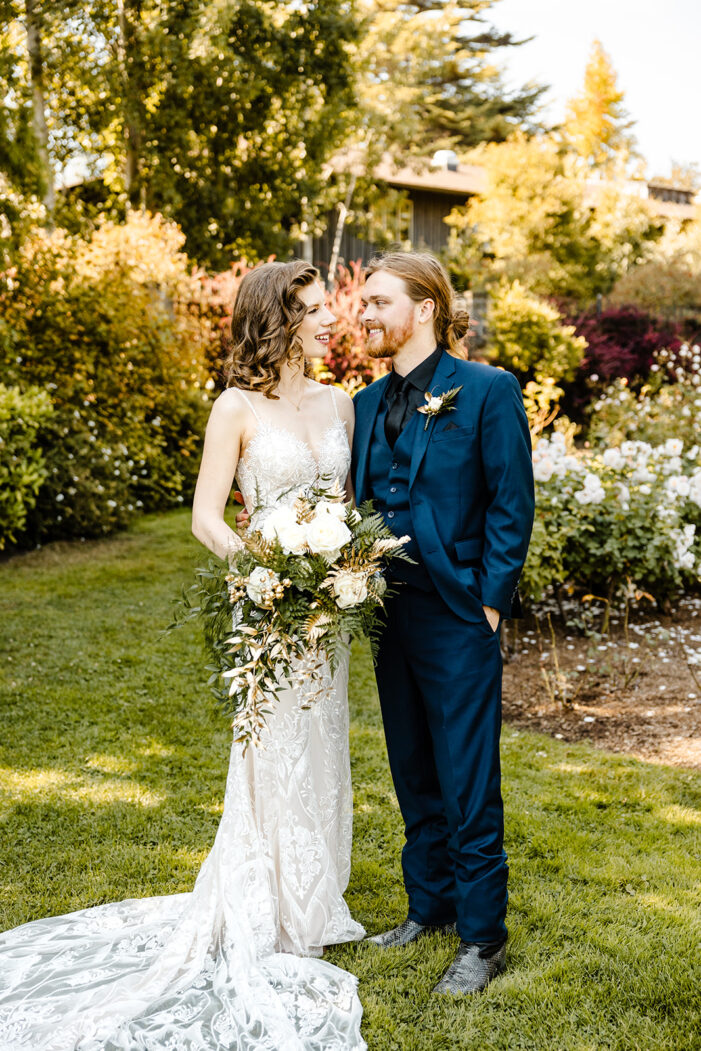 bride and groom pose in rose garden