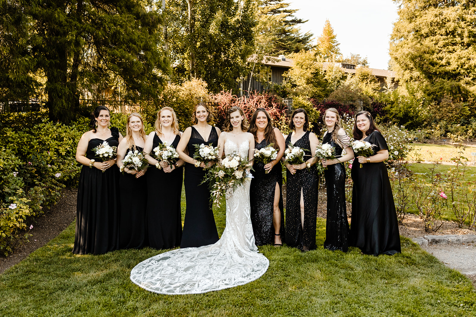 bride stands with bridesmaids in black dresses