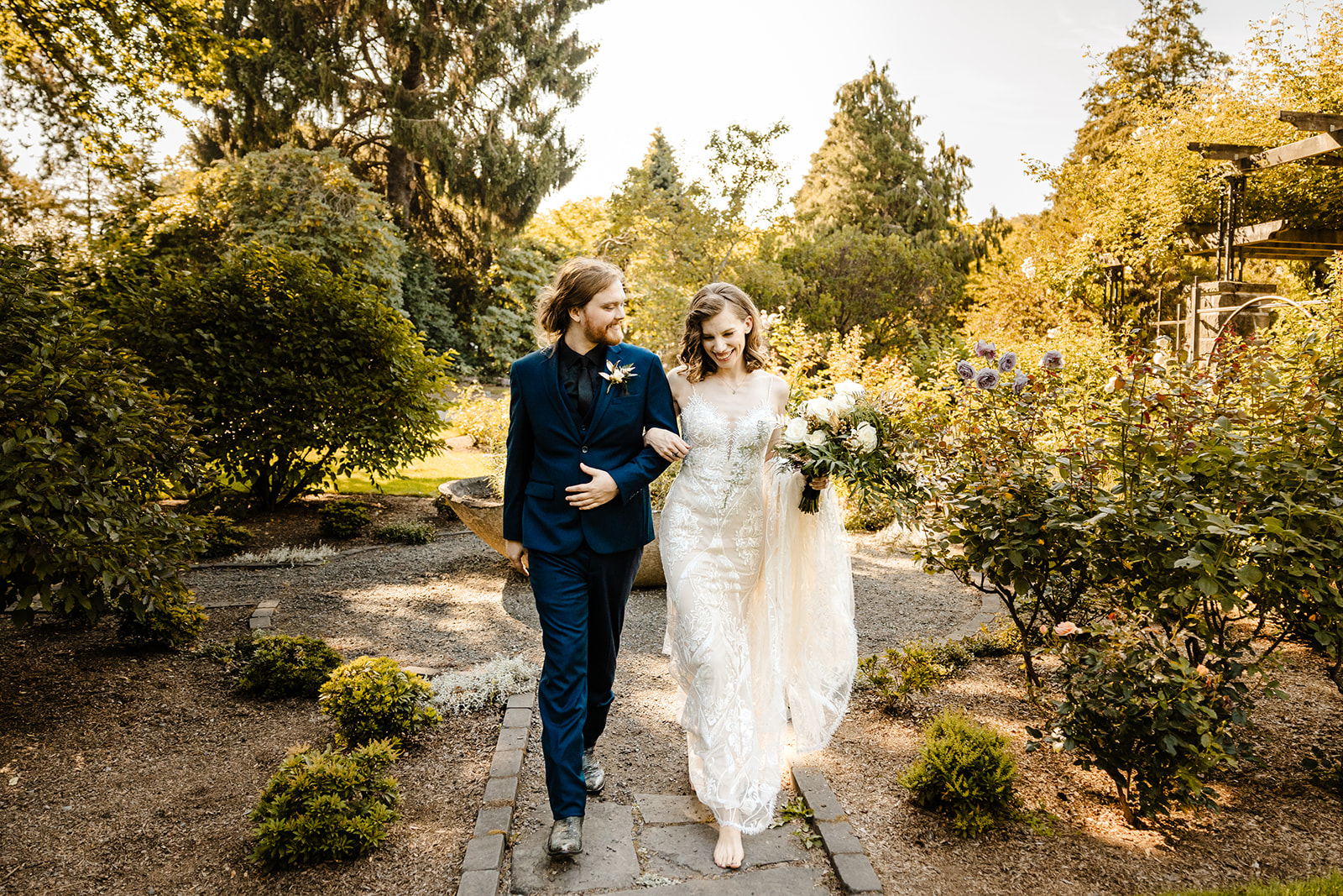 bride and groom walk through rose garden