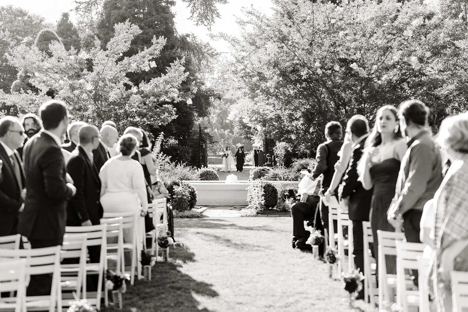 bride walks with father beyond fountain