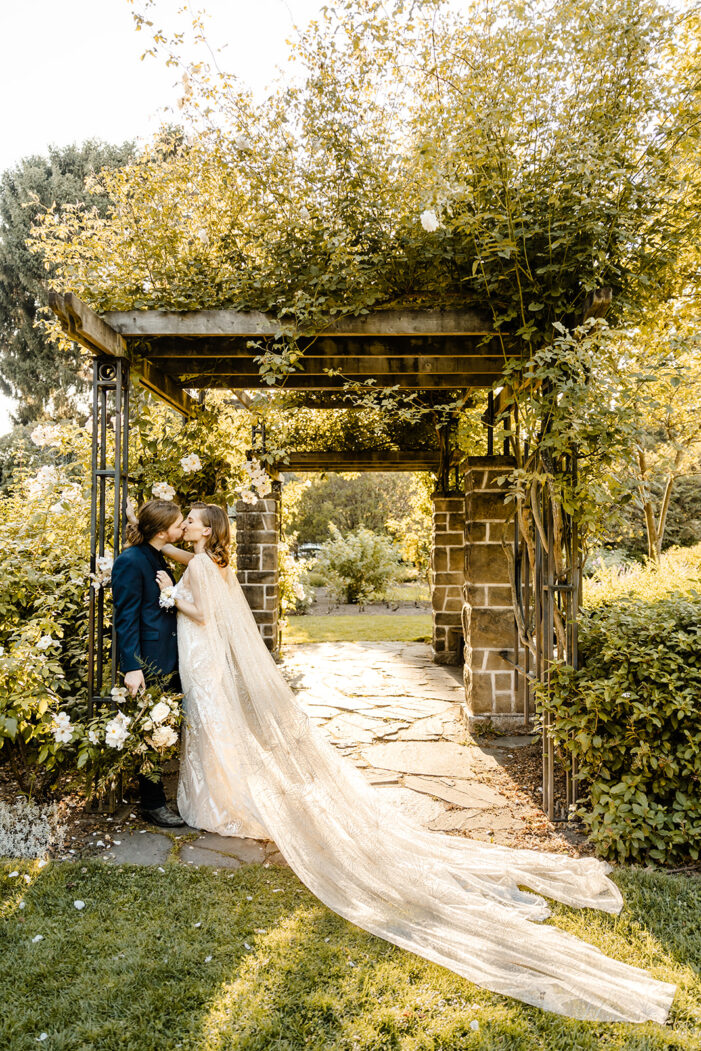 bride and groom cuddle in a rose garden