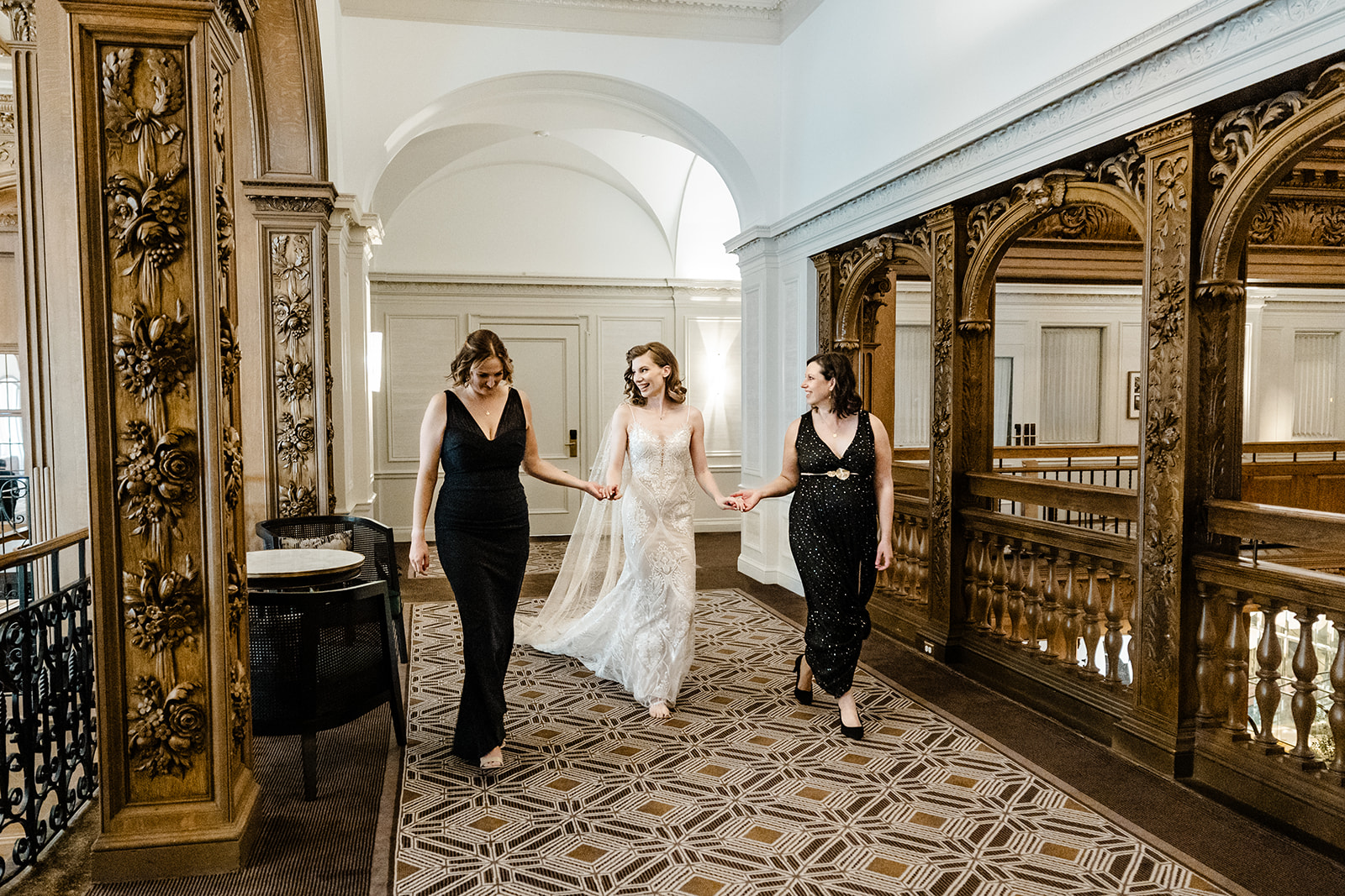 two bridesmaids assist bride in walking down hall