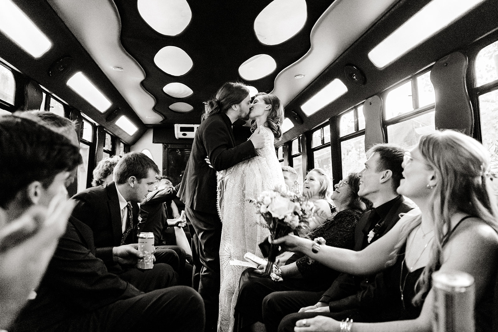 bride and groom kiss in party bus surrounded by friends