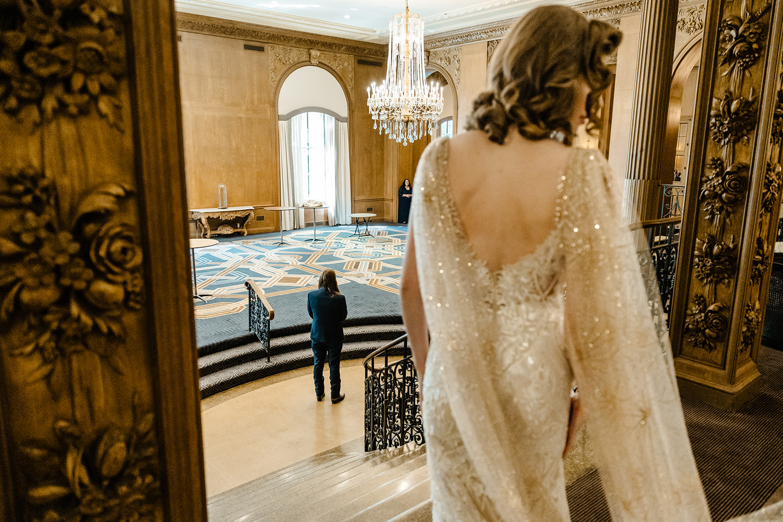bride stands at top of stairs looking down at man below