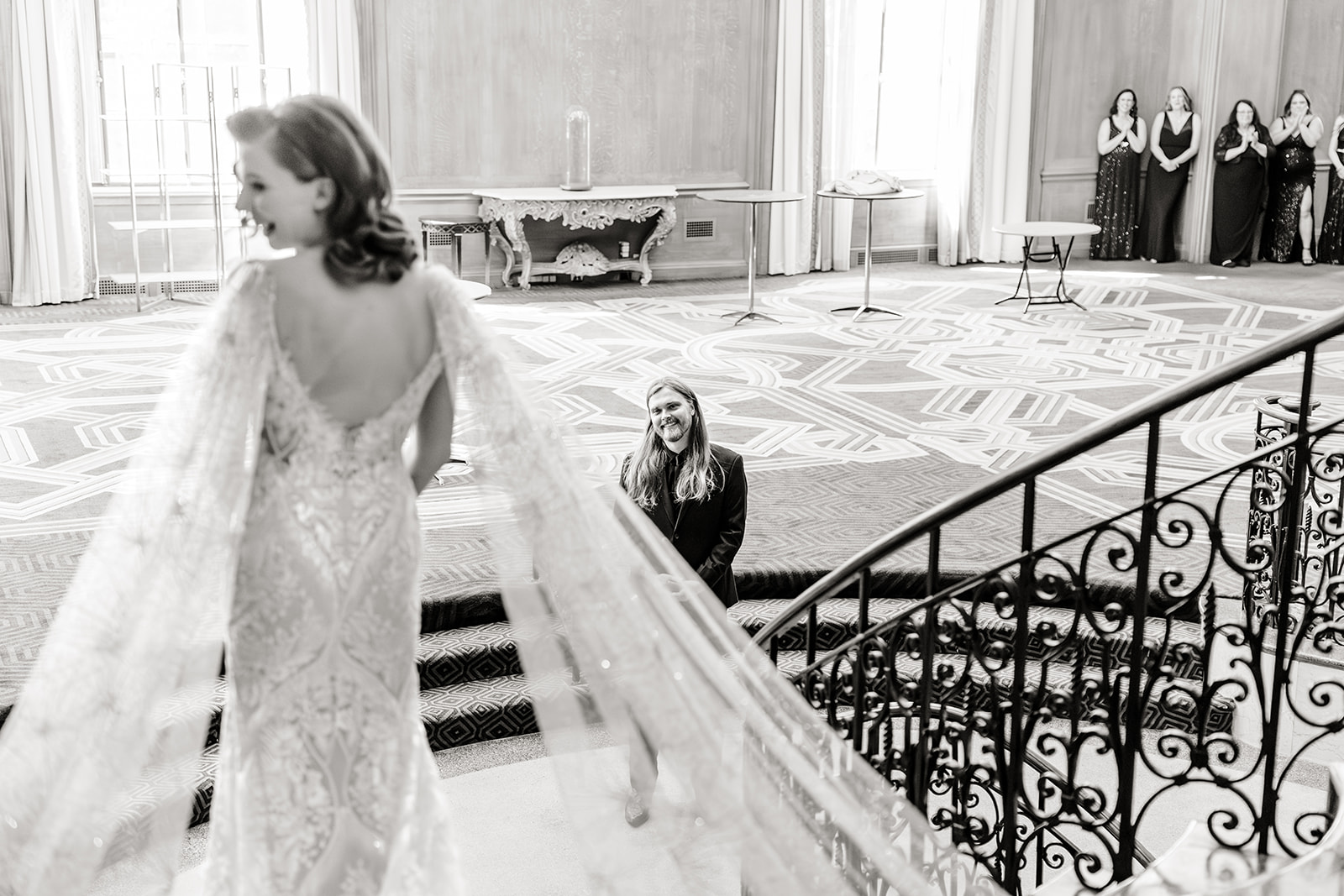 groom looks up at a bride standing at the top of stairs in Fairmont Hotel