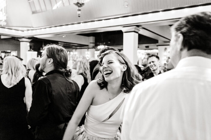 bride laughs and dances amongst wedding guests
