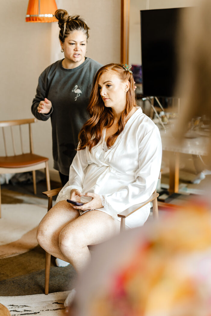 bride sits in makeup chair on wedding day