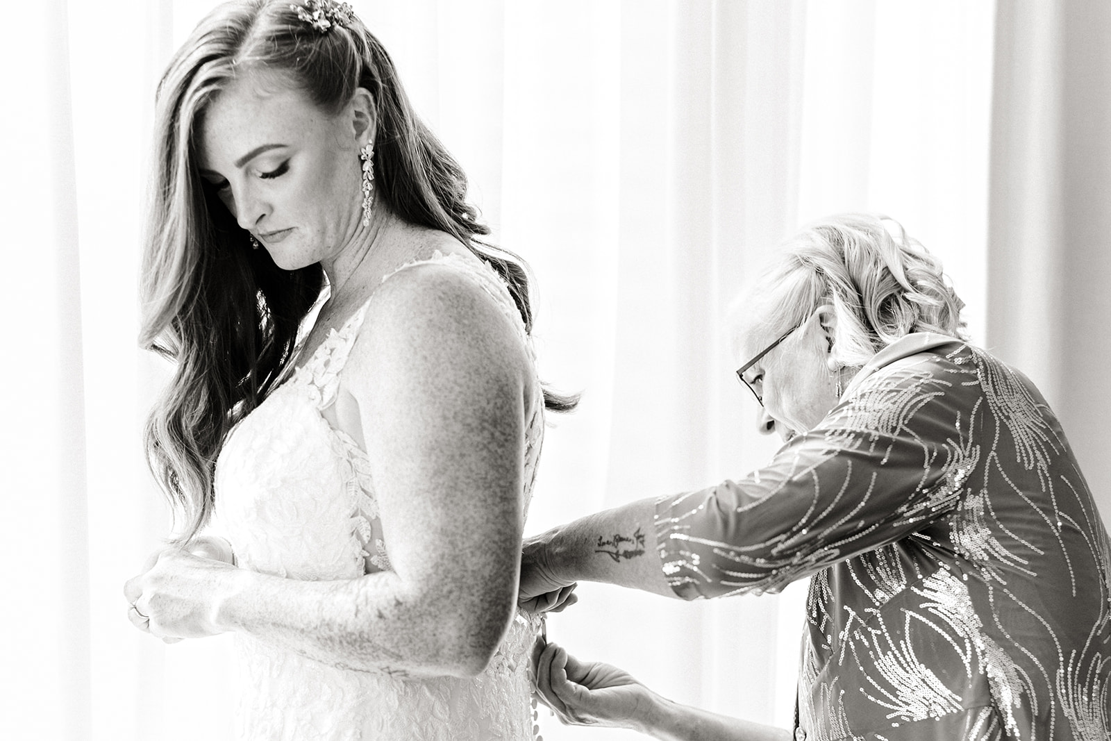 mom puts dress onto bride
