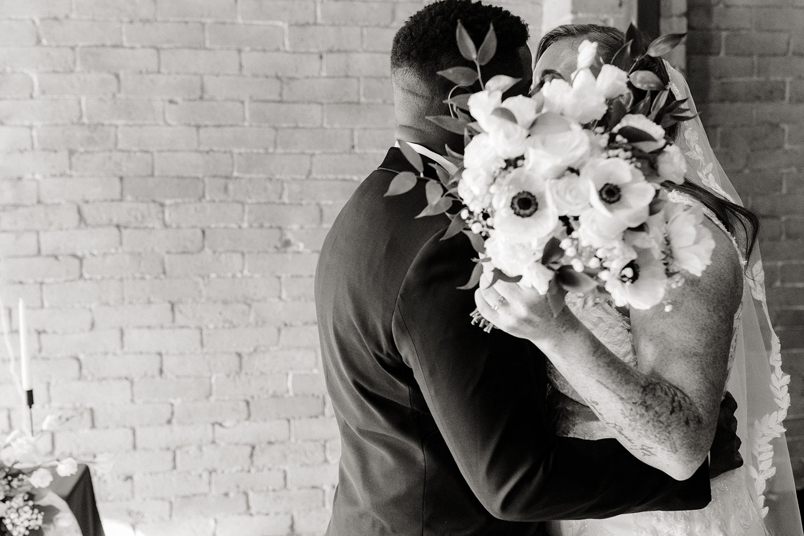 bride and groom kiss behind flowers