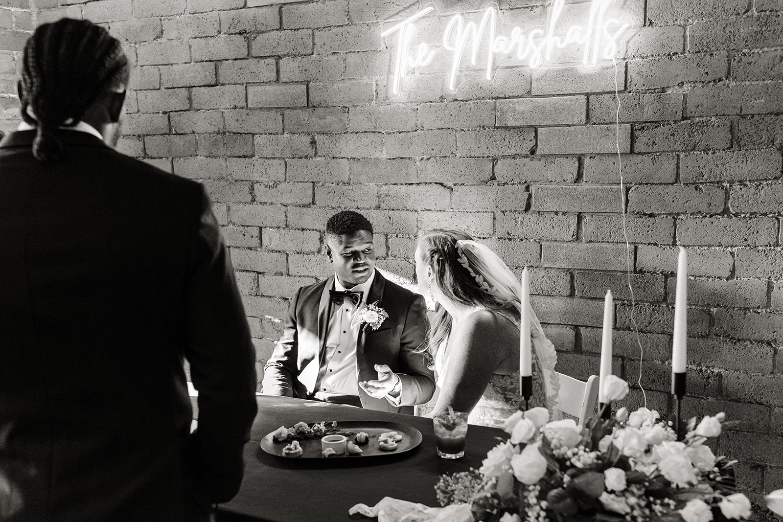 bride and groom look at each other as they sit at sweetheart table