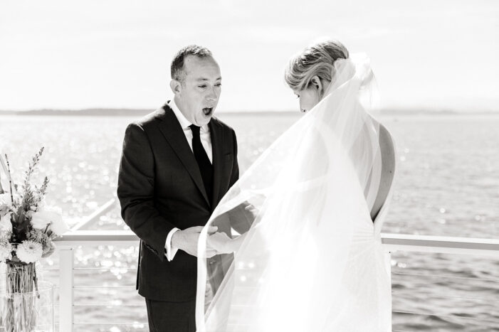 bride and groom stand on ocean view porch