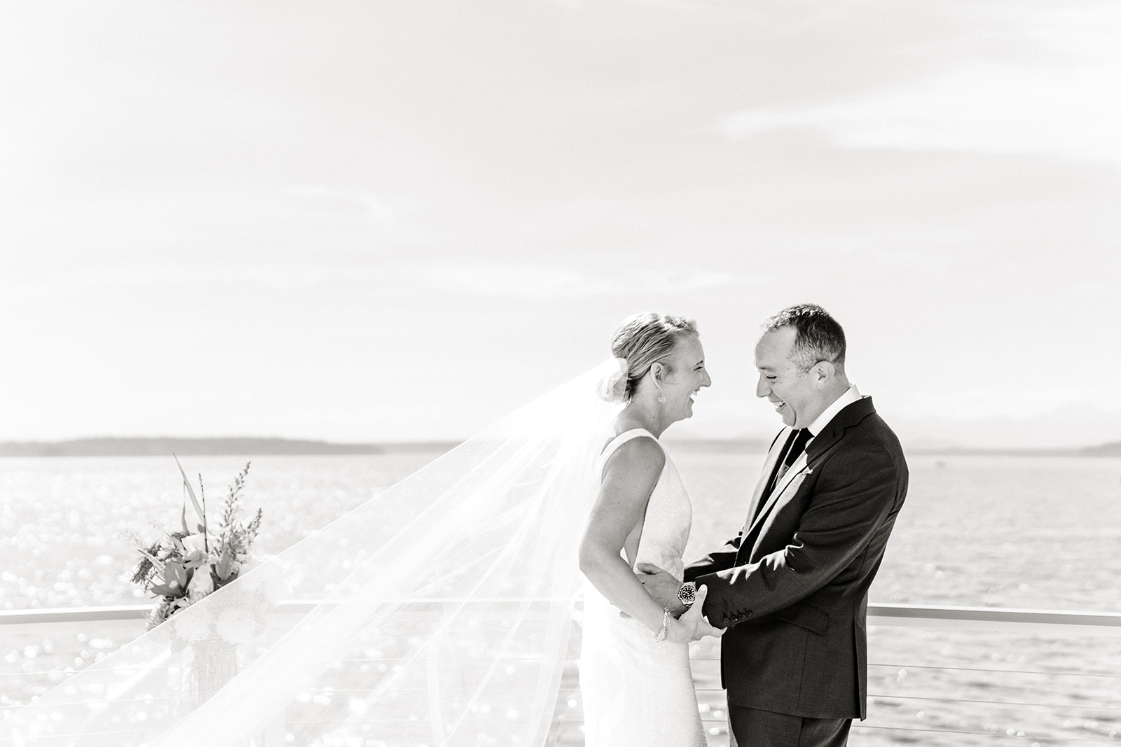 bride and groom stand on porch overlooking ocean