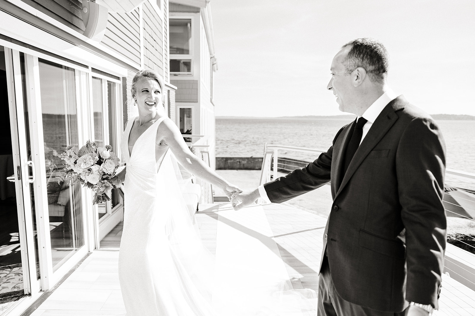 bride and groom walk across porch that overlooks ocean