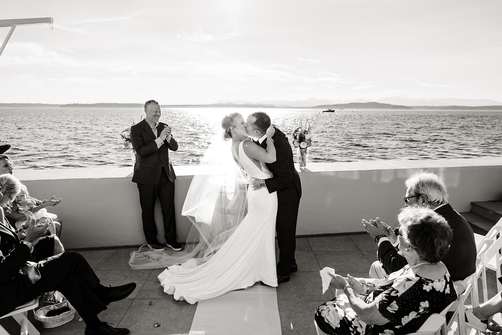 bride and groom kiss on porch overlooking ocean