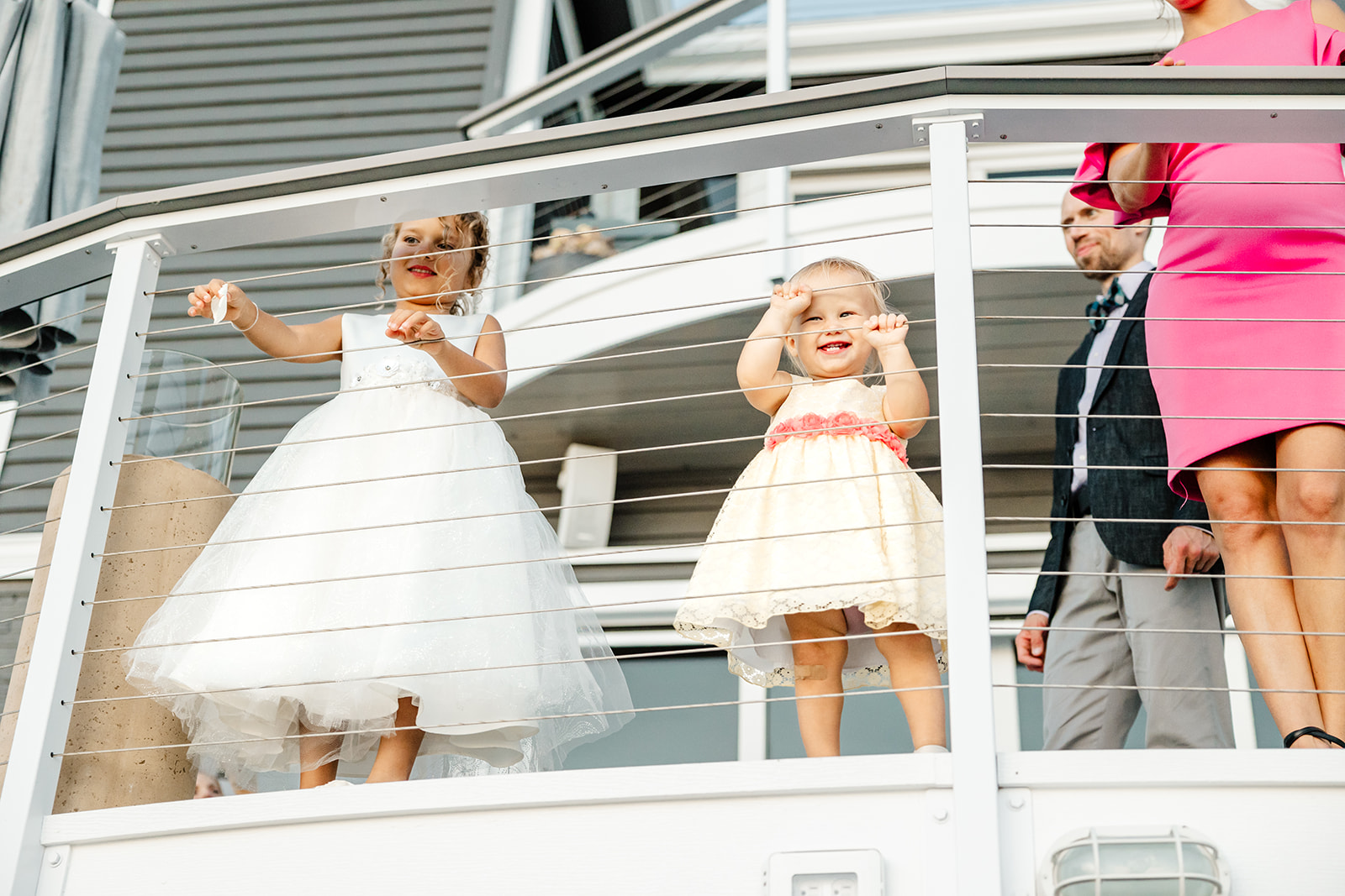 two little girls stand against railing looking down