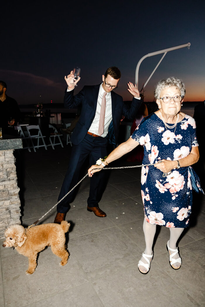wedding guests dance with ocean and sunset behind them