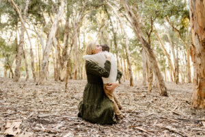 mom giving her son a hug during family mini session photos, surrounded by eucalyptus trees