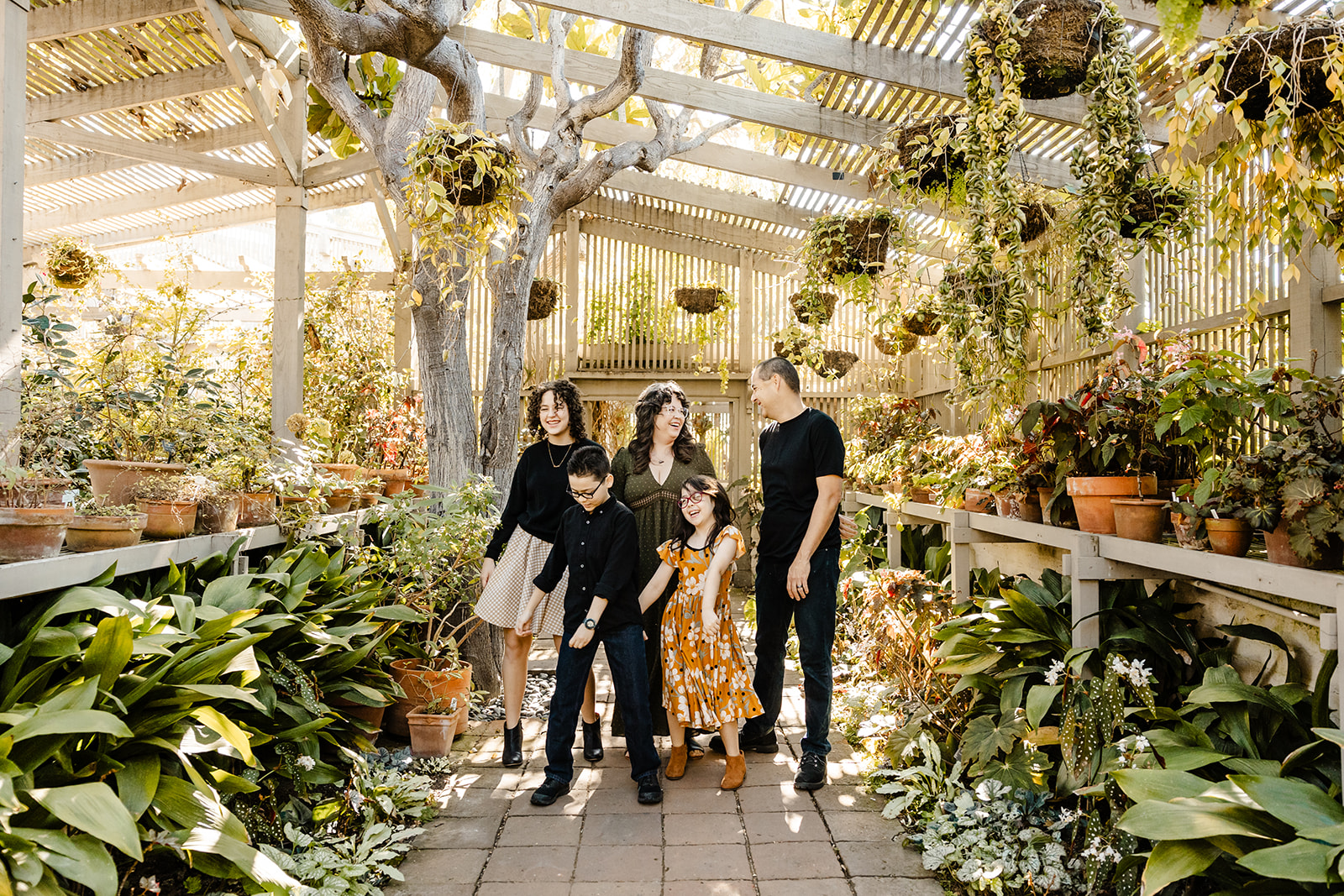 group photo in sun kissed greenhouse, kids dancing and playing with parents laughing
