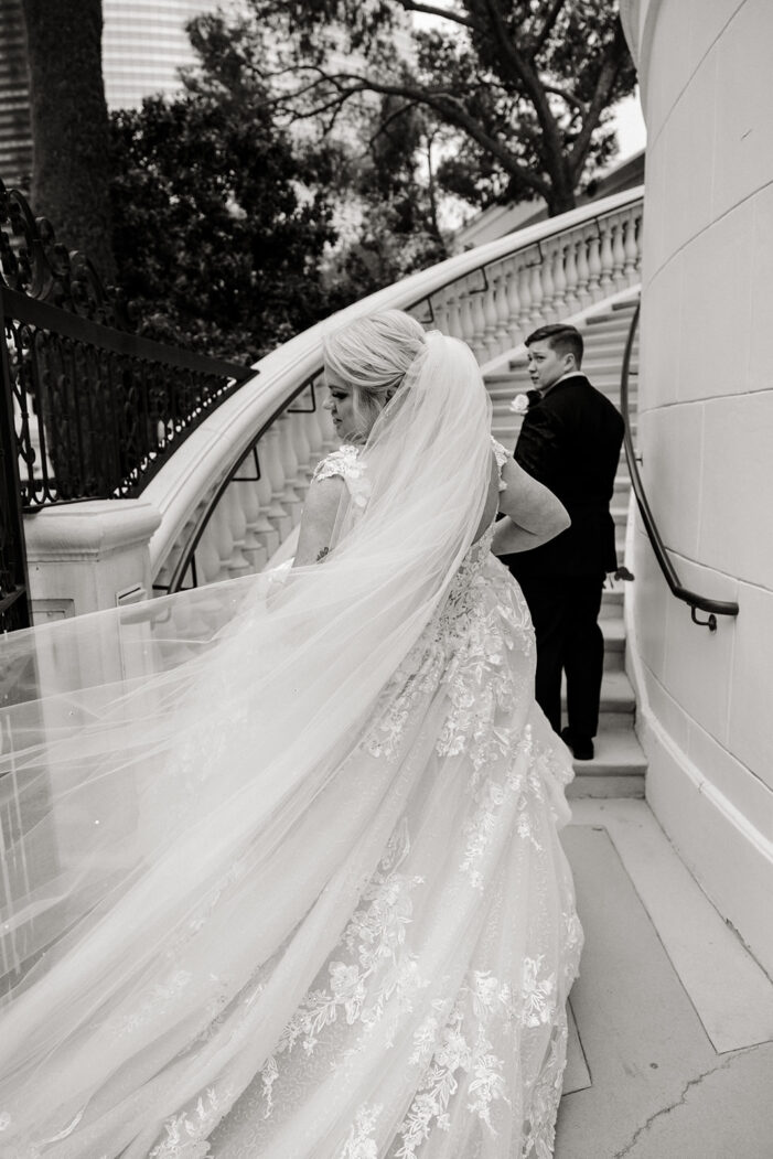 brides walk up stairs together with a veil flowing out behind them