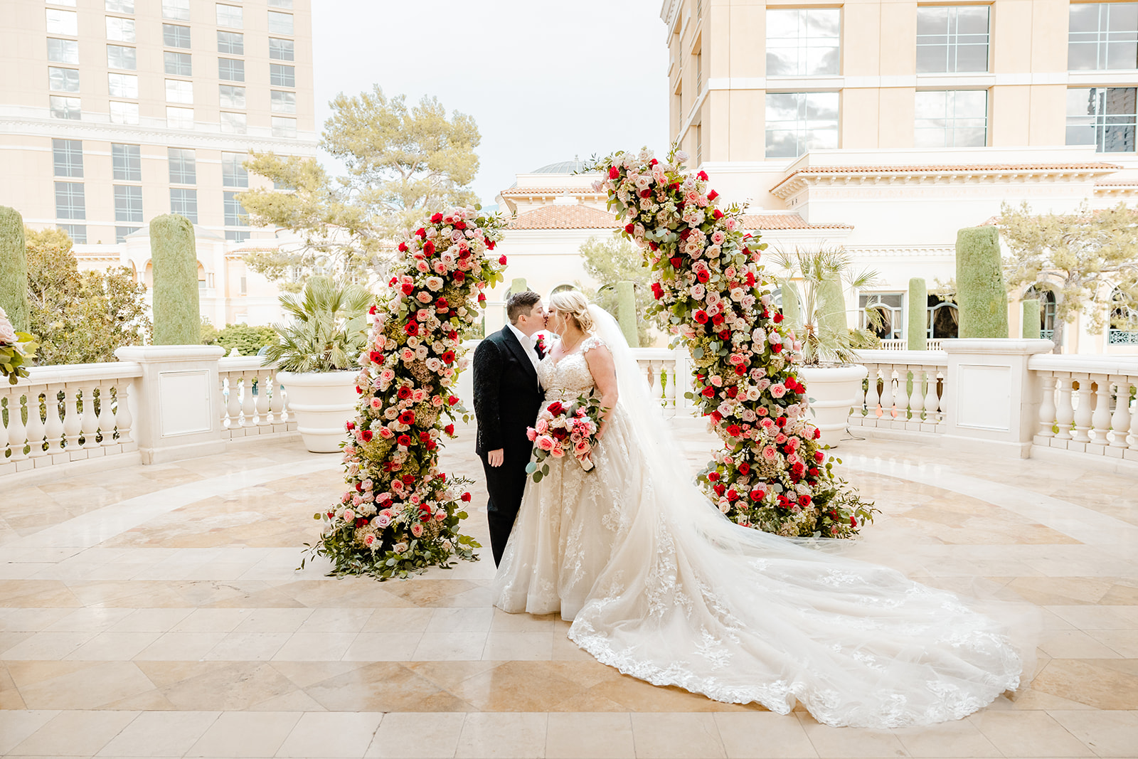 two brides pose between arches of flowers