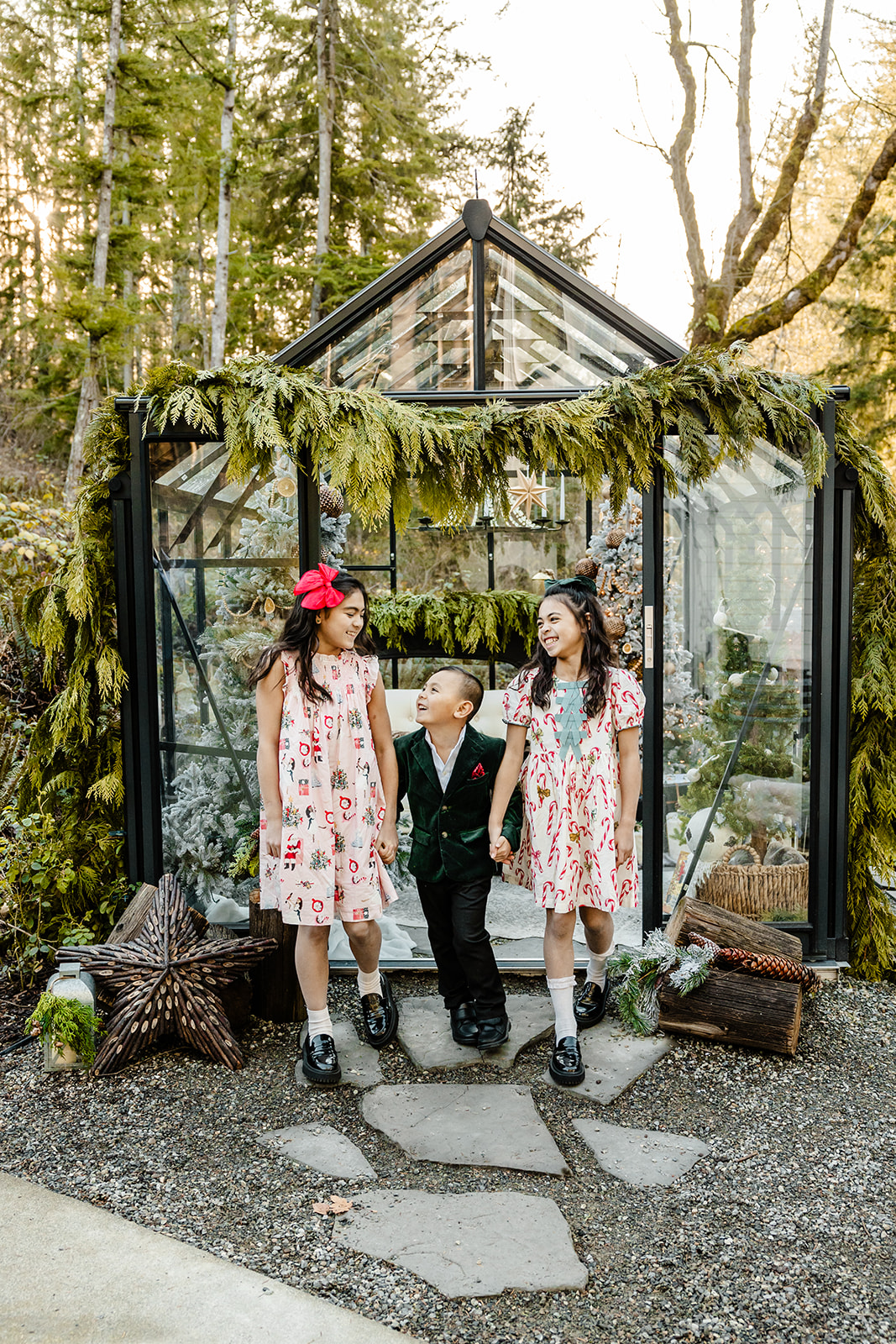 mini session family in front of greenhouse dressed in holiday attire, three kid siblings