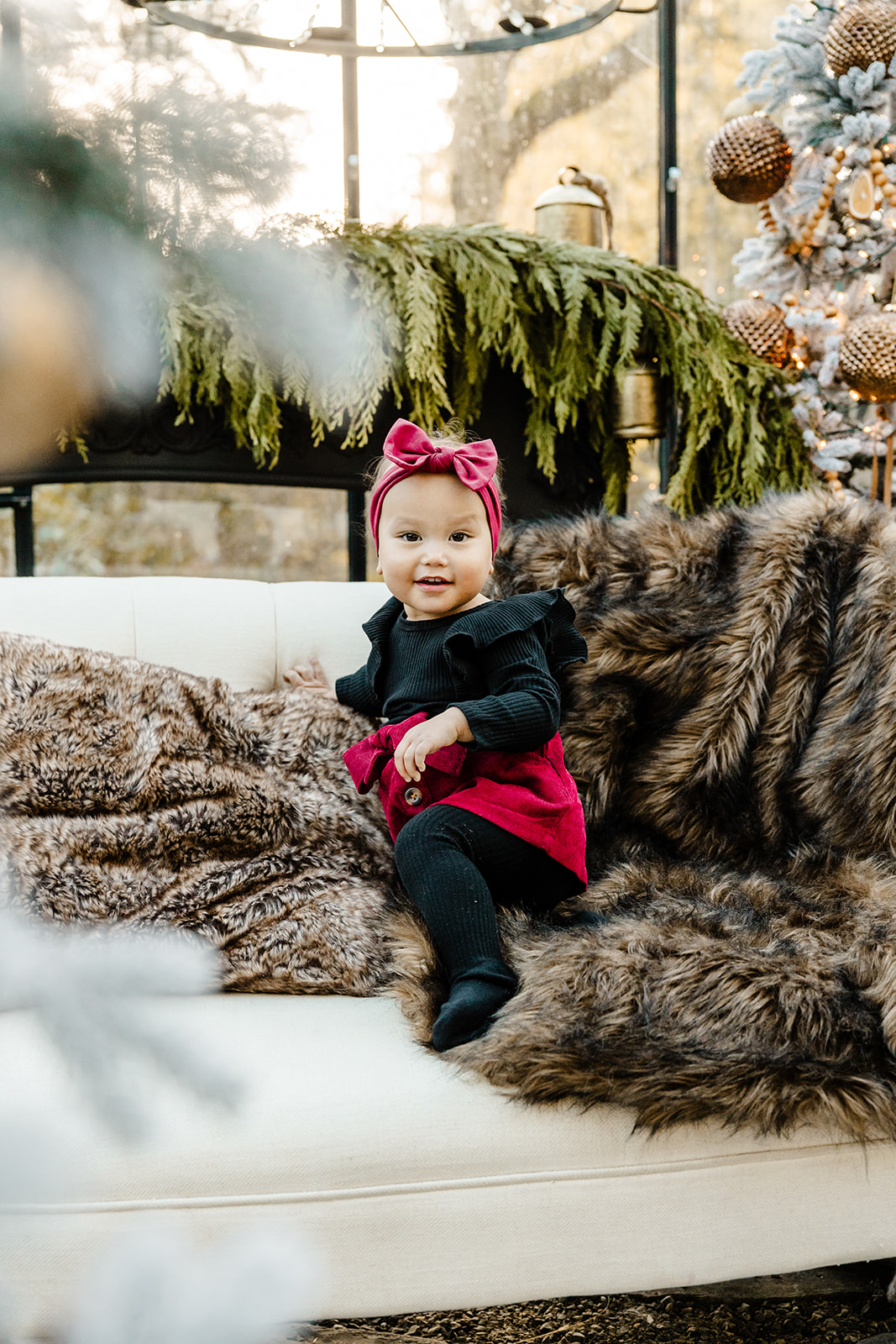 greenhouse family mini sessions in Seattle, WA, child on couch looking at camera dressed in black and burgundy holiday outfit