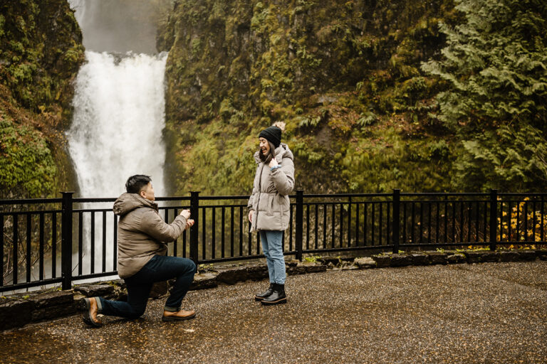 boy kneels in front of girl at multnomah falls