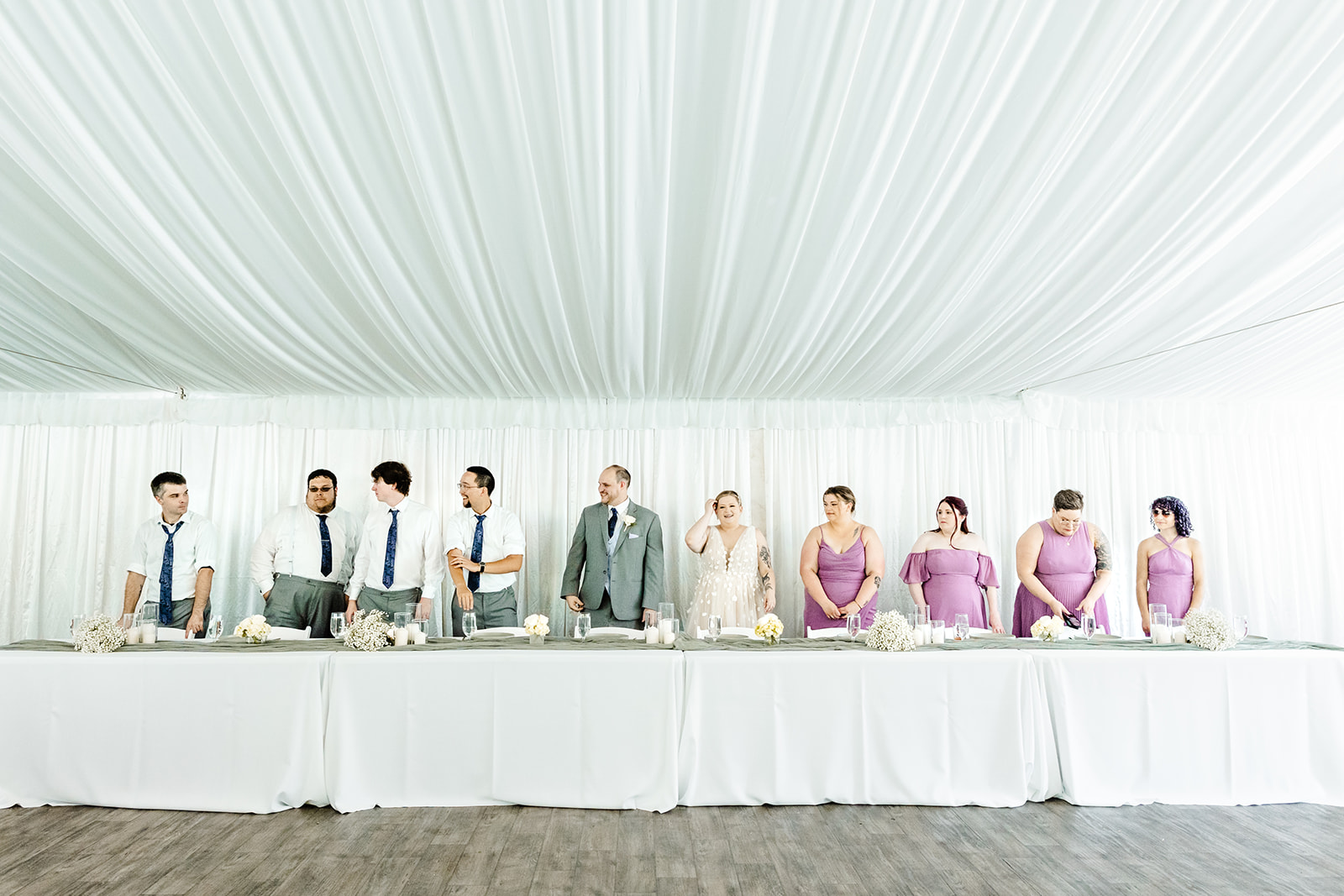 bride, groom and bridal party stand at table during reception
