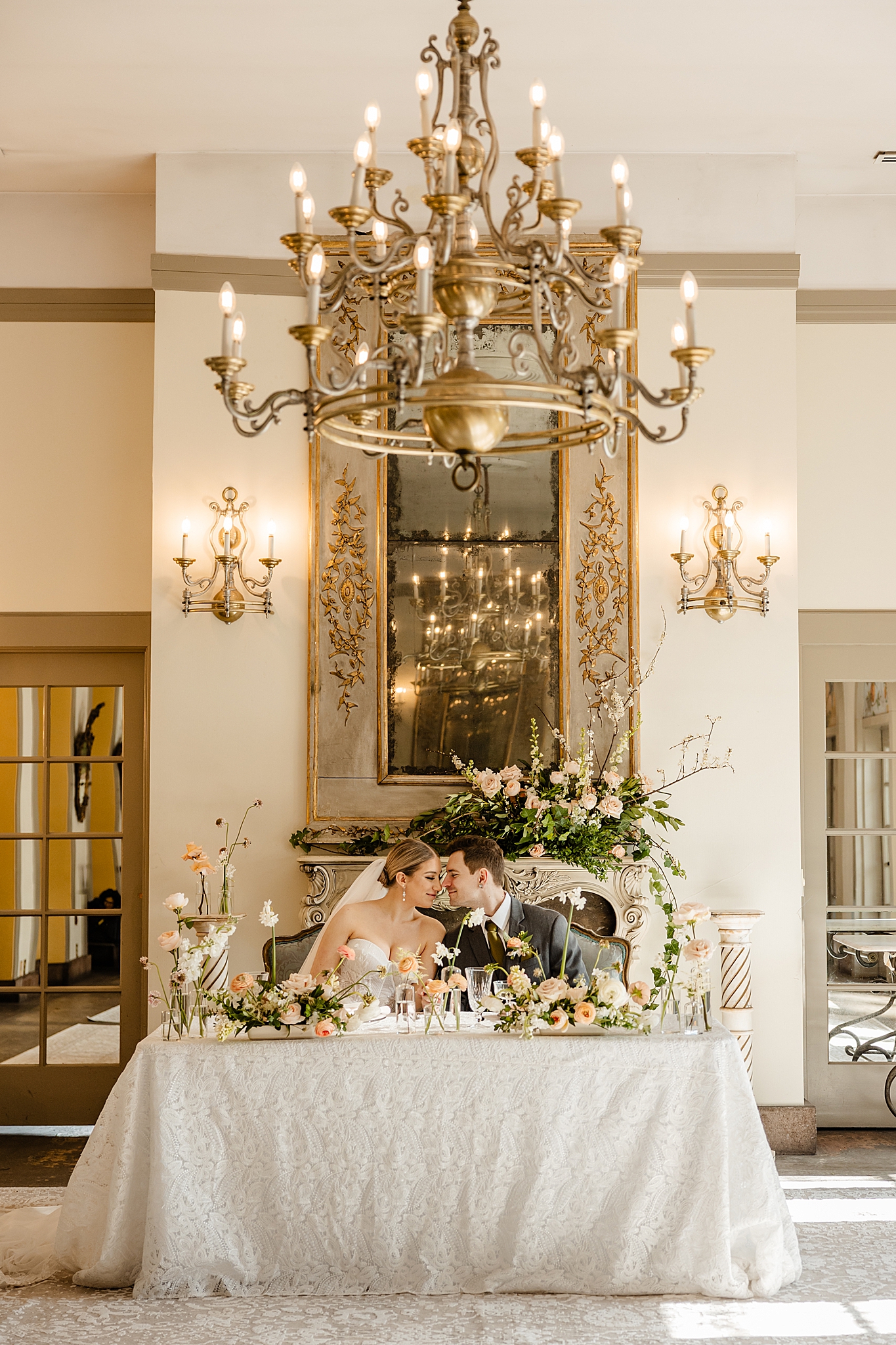 sweetheart table with lace tablecloth in front of a fireplace, surrounded by gold accents in ballroom at the ruins in seattle