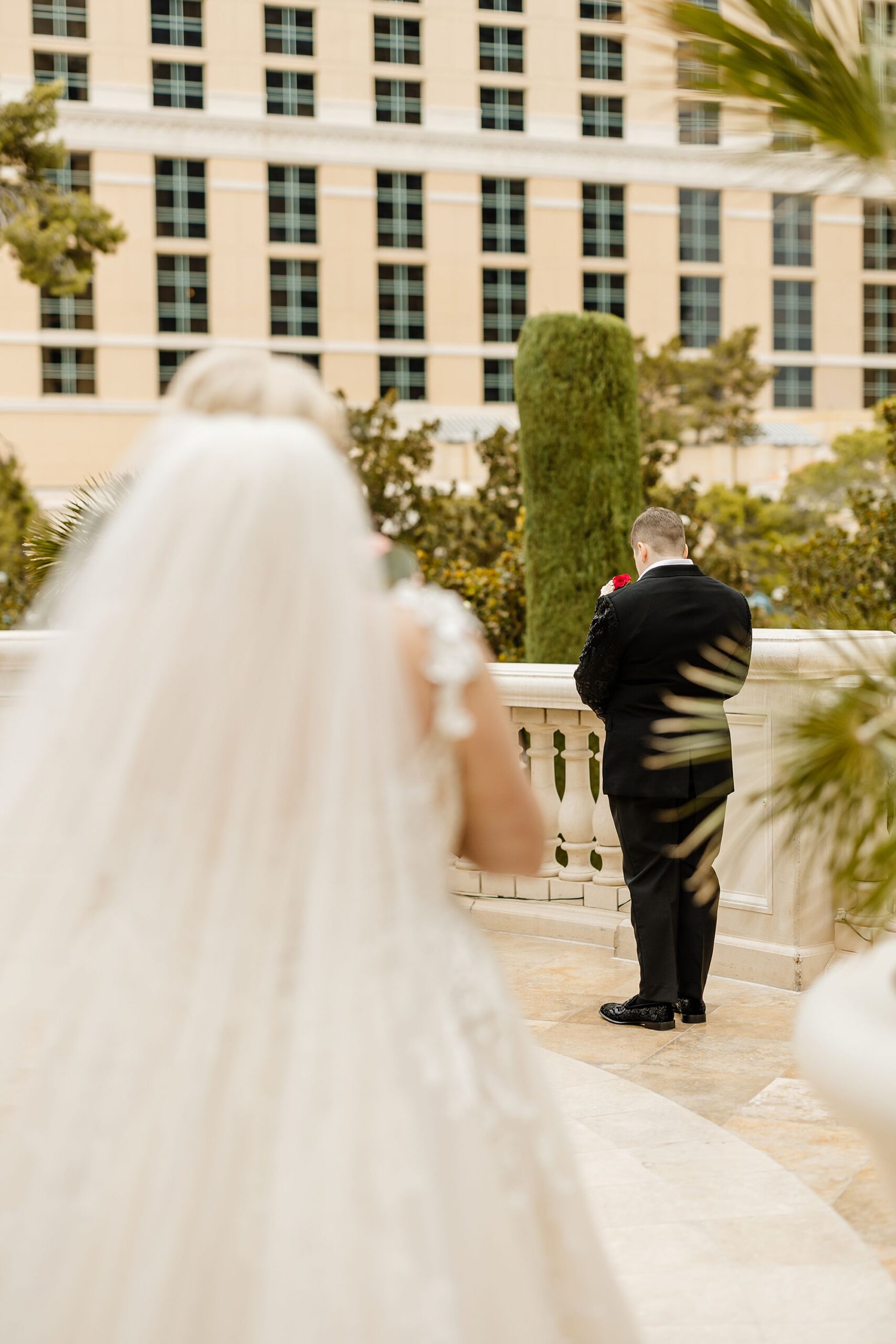 first look wedding photo building anticipation looking over brides shoulder to other bride waiting with back turned