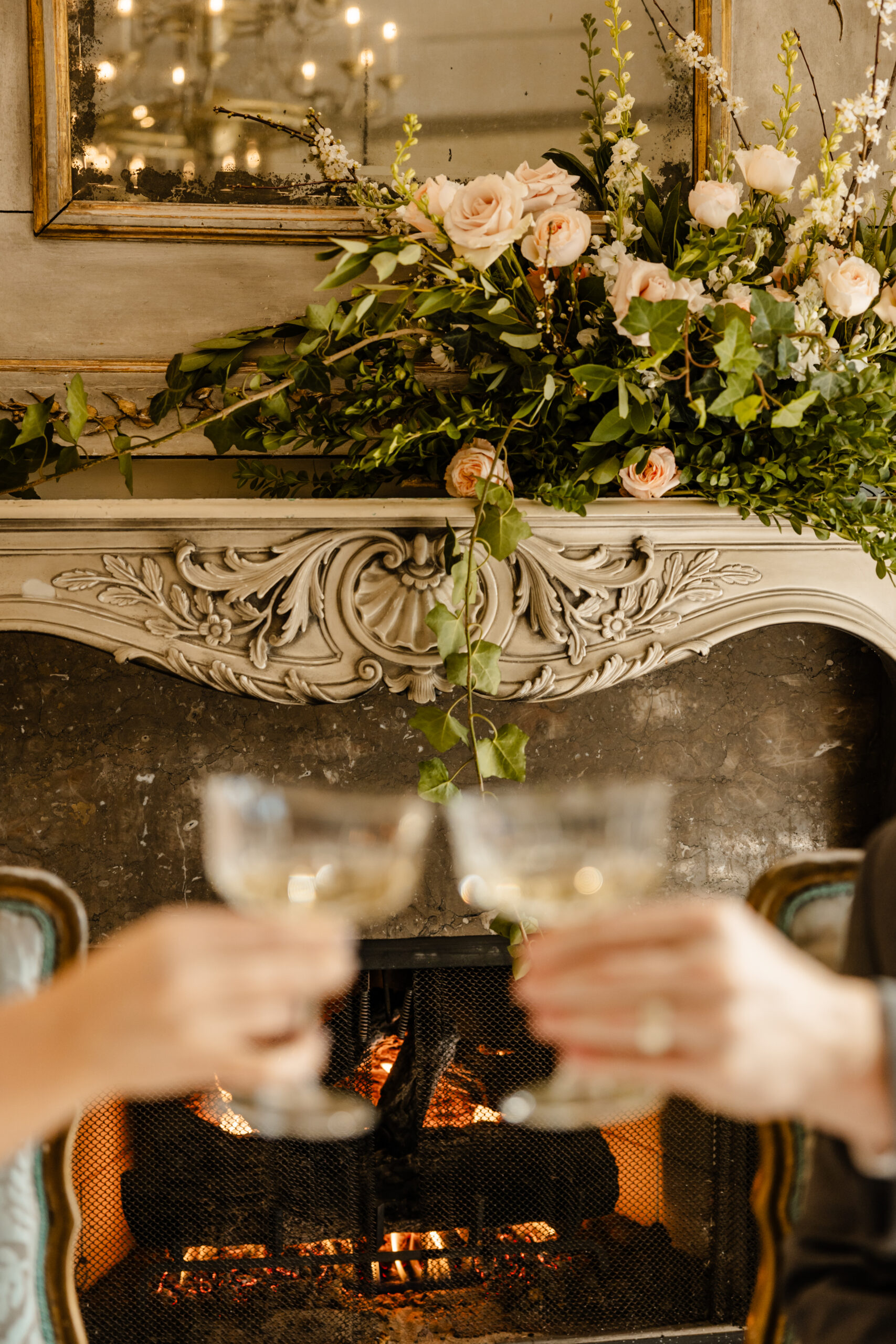 Seattle Wedding Photographer couple toasting champagne in front of fireplace adorned with florals