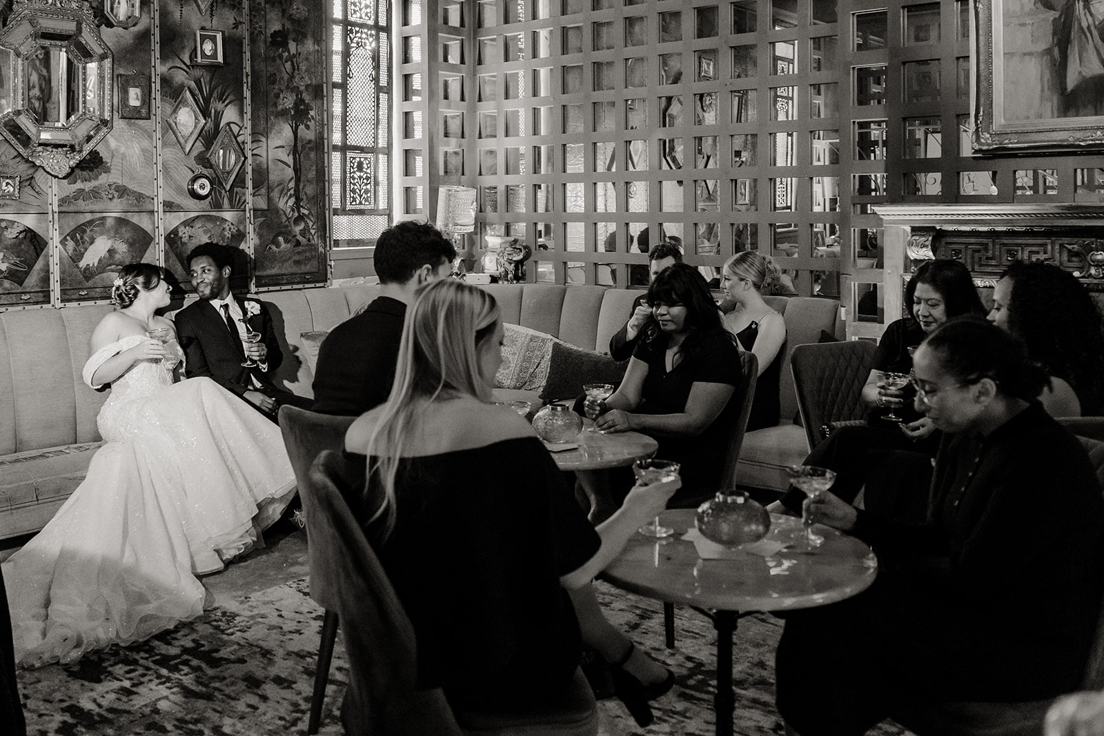 bride and groom sit amongst friends with champagne glasses